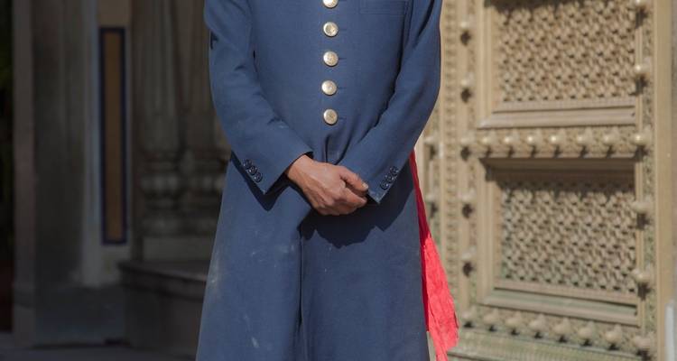 Personne bien habillée se tenant devant l'entrée d'un bâtiment patrimonial.