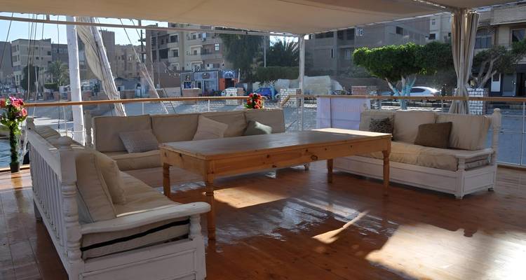 Outdoor seating area with cushions and trees in the background.