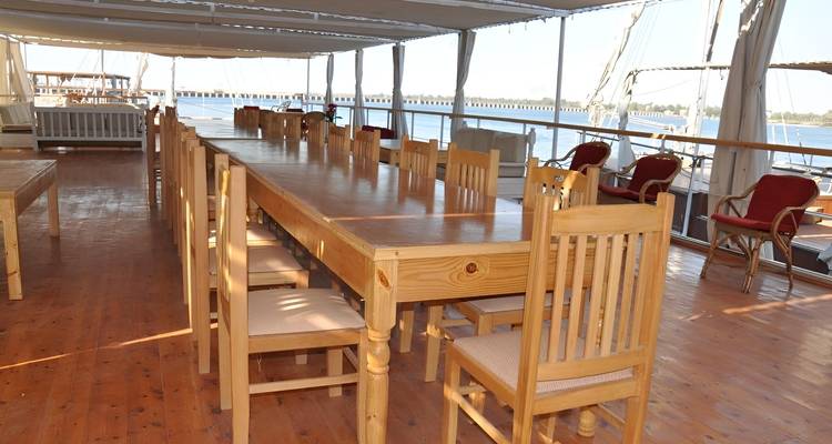 Dining area on a boat with tables and chairs.