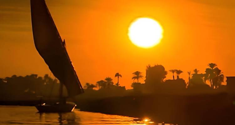 Traditional felucca sailing at sunset.