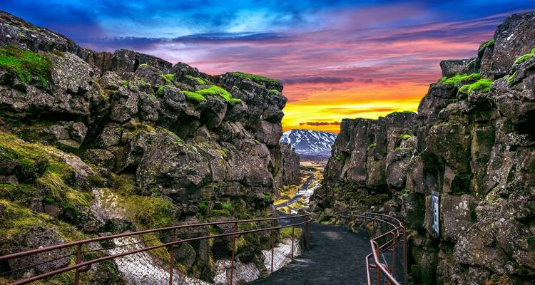 Pathway through rocky cliffs with a colorful sunset.