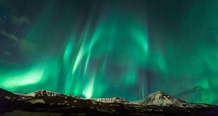Northern Lights illuminating a snowy mountain landscape.