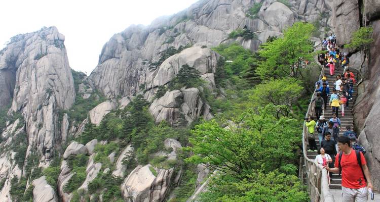 Des touristes faisant de la randonnée sur un sentier de montagne avec des pics rocheux.