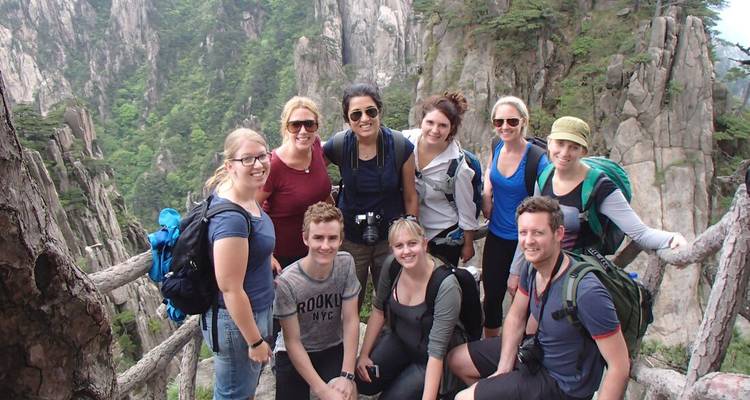 Groupe de voyageurs posant avec des montagnes en arrière-plan.