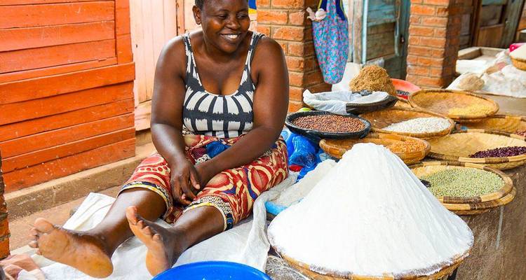 Smiling woman selling a variety of grains at a market.