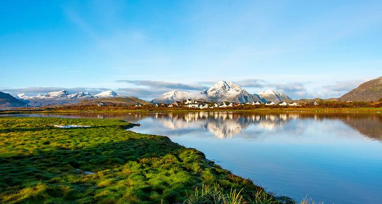 Scenic view of a village with snowy mountains in the background.