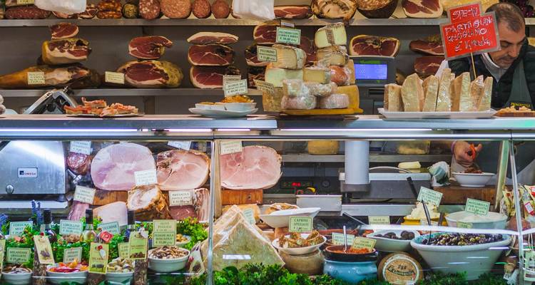Un étal de marché présentant une variété de viandes et de fromages.