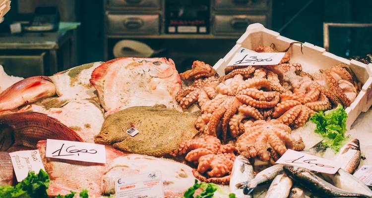 Une variété de fruits de mer incluant du poulpe et du poisson exposée sur un étal de marché.