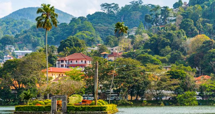 A scenic view of a landscaped city with lake and hills.