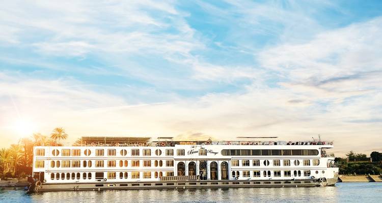 Bateau de croisière blanc sur le fleuve Nil pendant la journée avec un ciel dégagé.