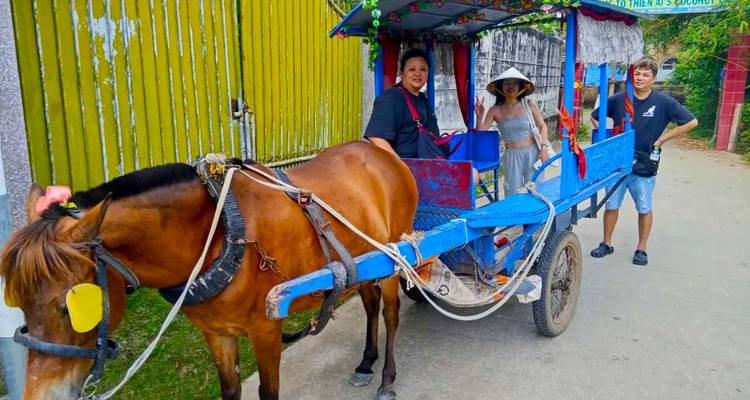Des touristes sur une charrette tirée par des chevaux dans un cadre rural vietnamien.