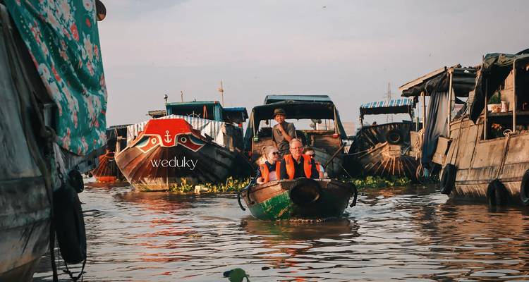 Marché flottant avec des bateaux sur une rivière, un bateau avec le texte visible 'weduky'.