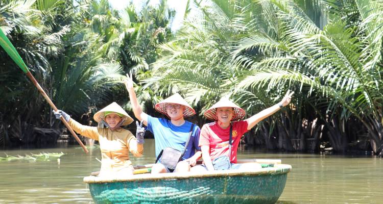 Trois personnes dans un bateau de bambou circulaire au milieu d'une végétation luxuriante.