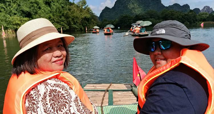 Deux personnes profitant d'une promenade en bateau sur une rivière entourée de montagnes calcaires.