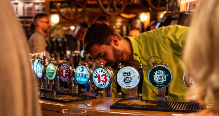 Bar avec différents robinets à bière et un barman.