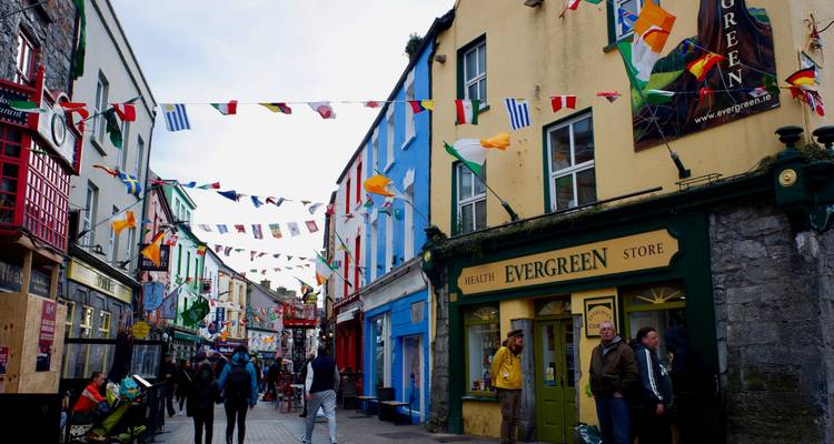 Rue colorée avec des boutiques et des gens qui marchent.