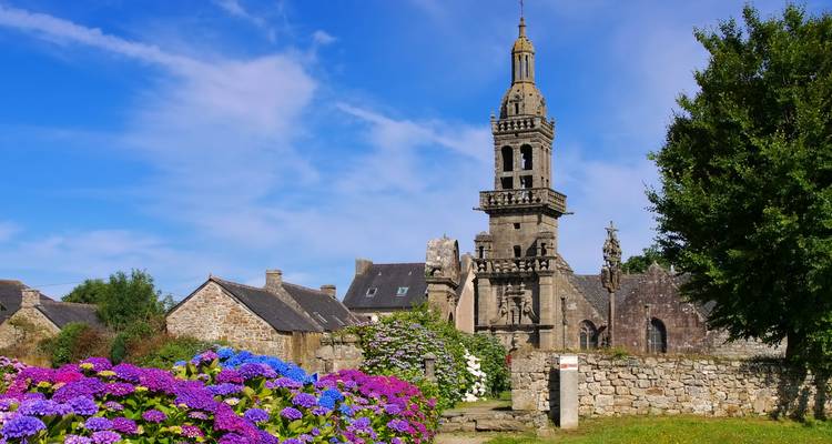 Église traditionnelle en pierre avec des fleurs au premier plan.