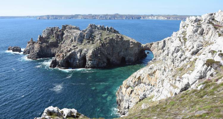 Falaises côtières spectaculaires avec des arches et une eau bleue cristalline.