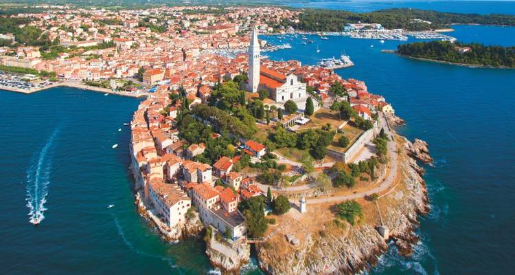 Vue aérienne de la péninsule de la vieille ville de Rovinj avec le clocher de l'église entouré par la mer d'un bleu profond