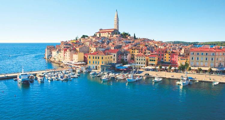 Vue du port du front de mer coloré de Rovinj dominé par l'église au sommet de la colline sous un ciel dégagé