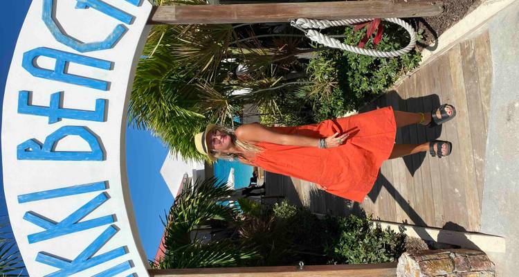 Personne posant sous une arche d'entrée de plage.