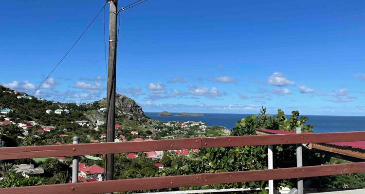 View of houses and sea with hills under a clear blue sky.