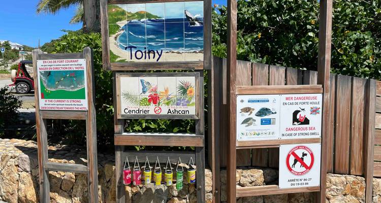Signs indicating safety and warnings near a beach.