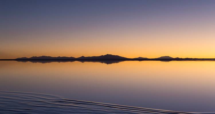 Sonnenuntergang über der Salar de Uyuni, die Berge reflektierend.