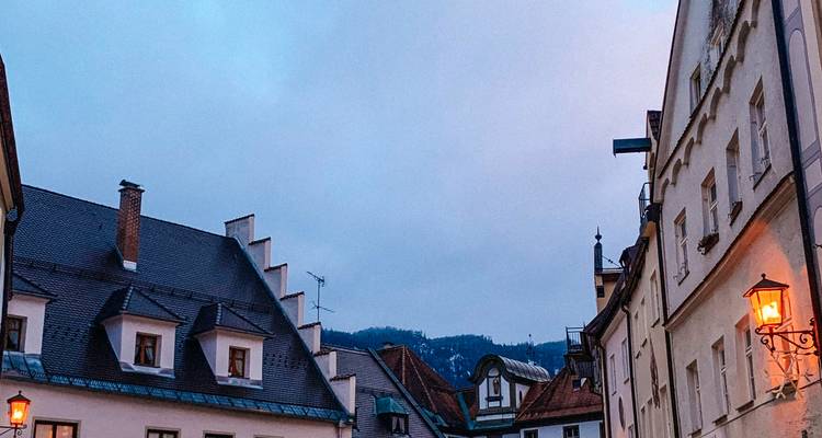 Evening view of a town street with buildings and lit lamps.