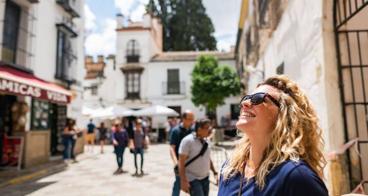 A woman enjoying sunlight in a charming street with other people walking.