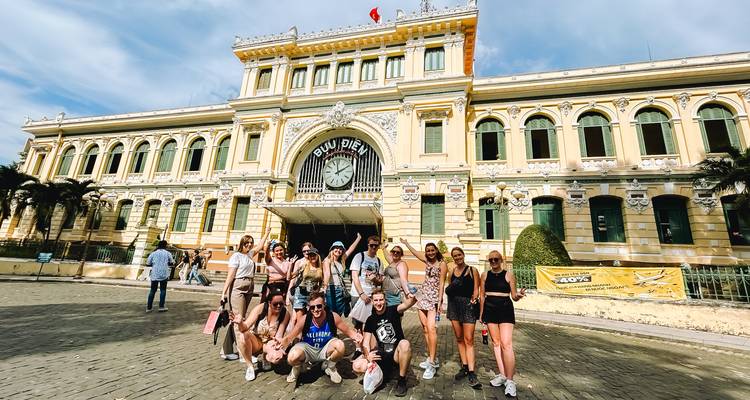 A large group of people posing in front of a historic yellow building.