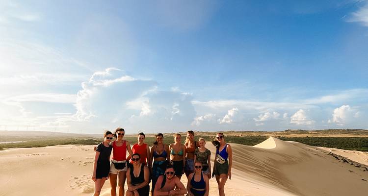 Group of people posing on sand dunes under a clear sky.