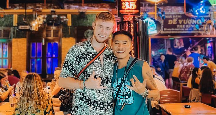 Two friends posing in a vibrant indoor market or bar setting.