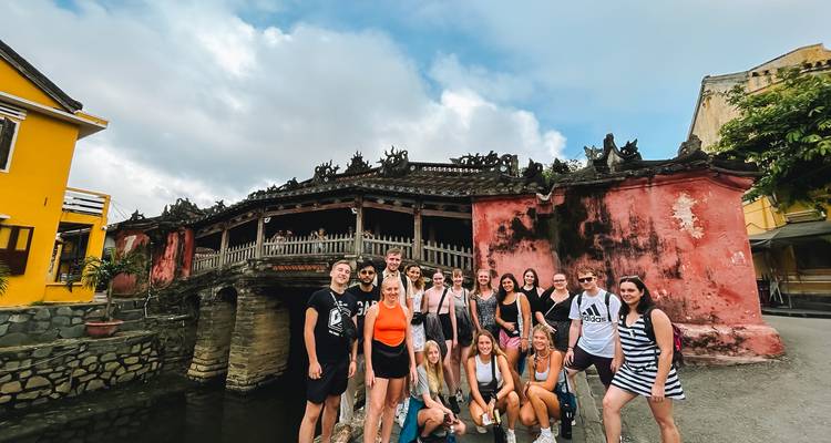 Group of tourists standing in front of a historic bridge in Hoi An.