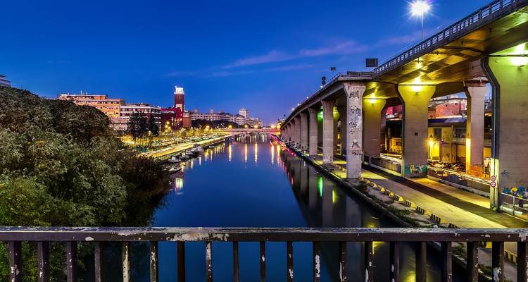 Paysage urbain avec un canal et des bâtiments modernes la nuit.