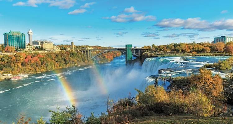 Niagarafälle mit einem Regenbogen und umliegenden Gebäuden.