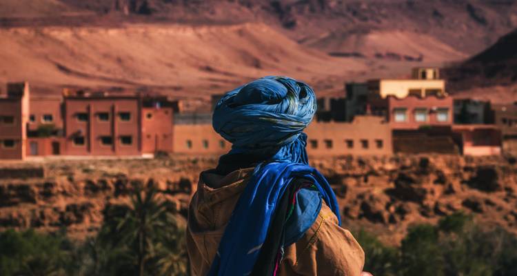 Person in traditioneller Kleidung blickt auf Wüstendorf.