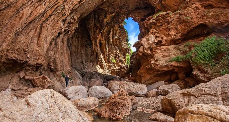 Felsige Schlucht mit einem kleinen Bach und einer wandernden Person.