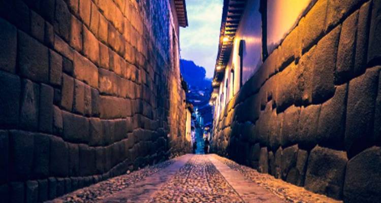 Une ruelle étroite pavée de galets avec des murs illuminés.