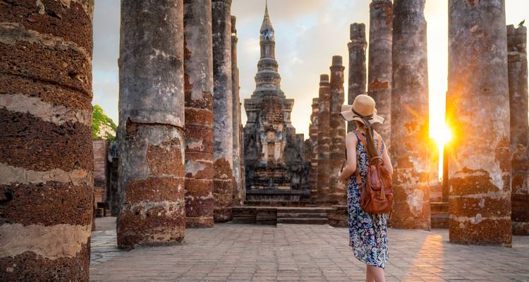 Une femme explorant un temple antique avec de hautes colonnes.