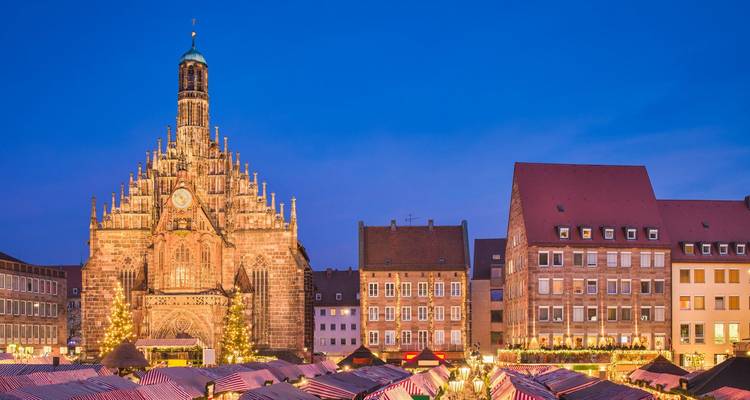 Marketplace in front of a Gothic church lit up in the evening.