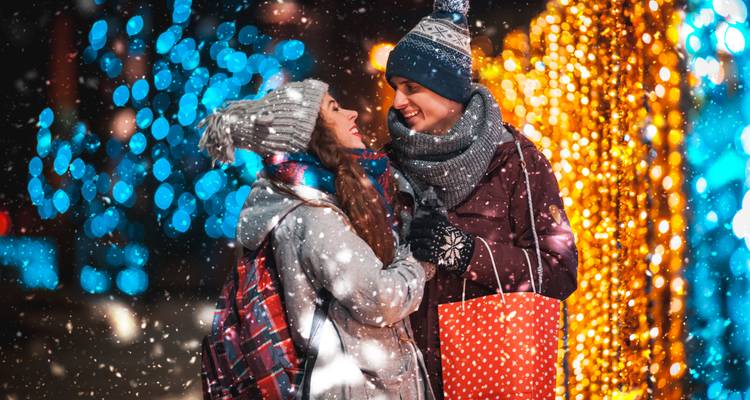 Couple profitant d'une soirée enneigée dans un marché festif.