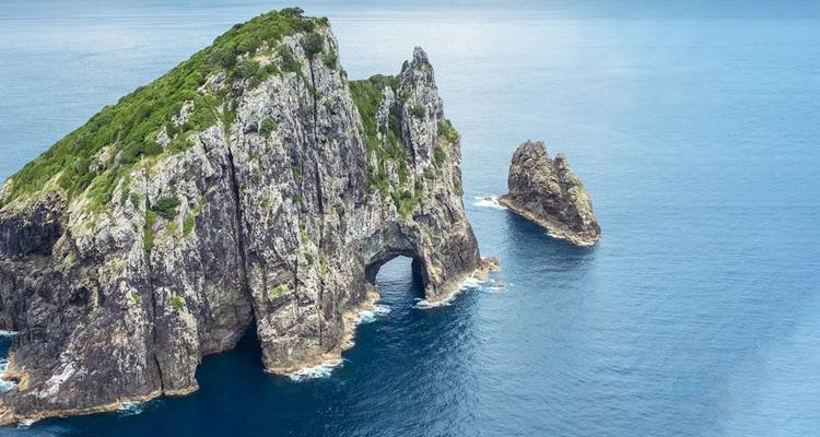 Rock formations with a natural arch by the ocean.