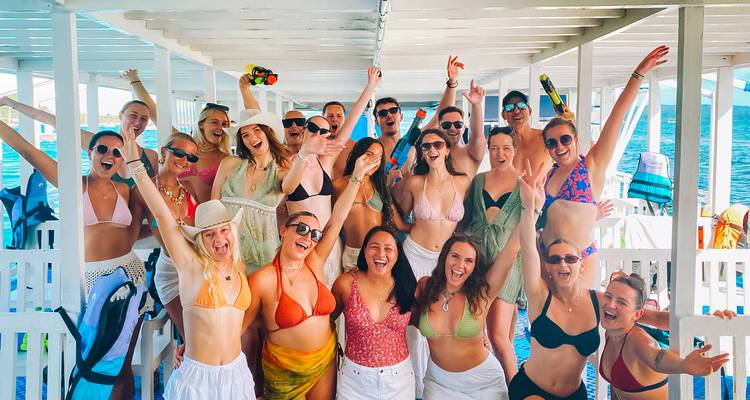 Large group of people posing inside a boat with open water visible behind.
