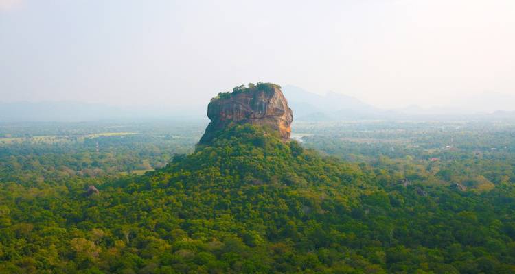 Luchtfoto van een weelderig groen landschap met een opvallende rotsformatie.
