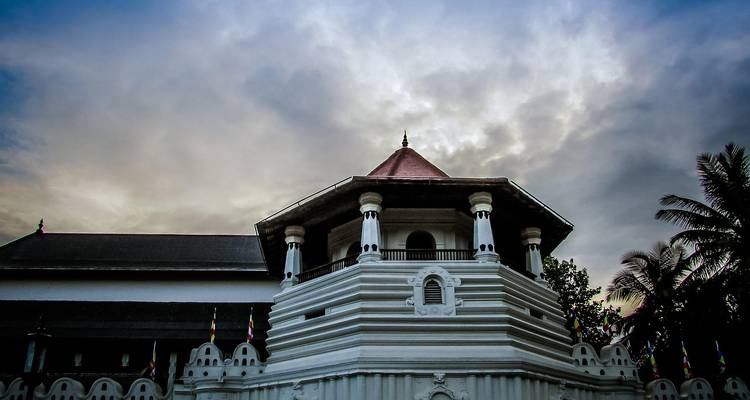 Een wit tempelgebouw met een koepel tegen een bewolkte hemel.