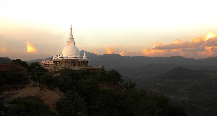 Een witte stoepa-tempel gelegen op een heuvel met schilderachtige uitzichten.