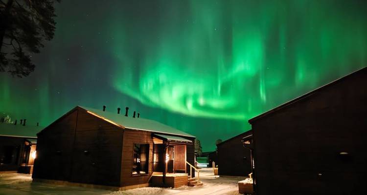Aurores boréales au-dessus de chalets la nuit.