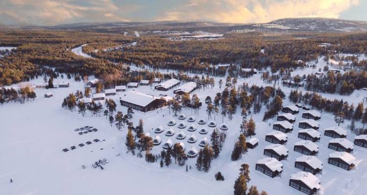 Vue aérienne d'une station enneigée entourée de forêt.
