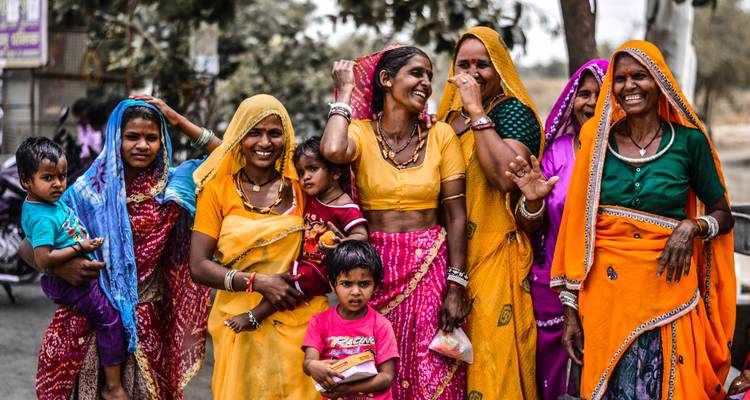 Groupe de femmes en tenues traditionnelles colorées posant avec des enfants.